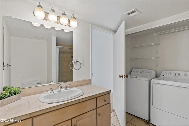 full bath with tile patterned floors, visible vents, toilet, a tile shower, and washing machine and clothes dryer