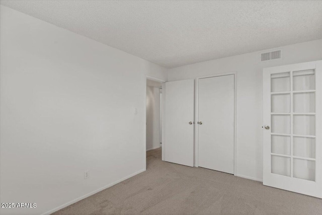 unfurnished bedroom with baseboards, carpet, visible vents, and a textured ceiling