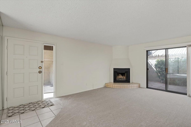 unfurnished living room featuring a textured ceiling, carpet, and a large fireplace