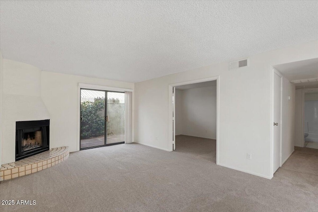 unfurnished living room with carpet, baseboards, visible vents, a textured ceiling, and a large fireplace