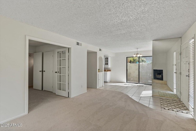 unfurnished living room featuring visible vents, a large fireplace, a chandelier, and carpet flooring