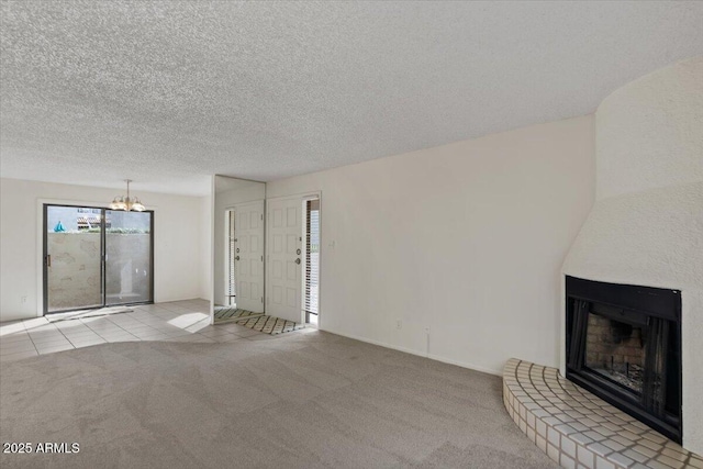 unfurnished living room featuring a textured ceiling, a large fireplace, an inviting chandelier, carpet flooring, and tile patterned flooring