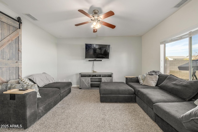 carpeted living room featuring a barn door and ceiling fan