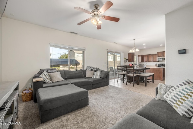 living room featuring ceiling fan with notable chandelier and light tile patterned floors