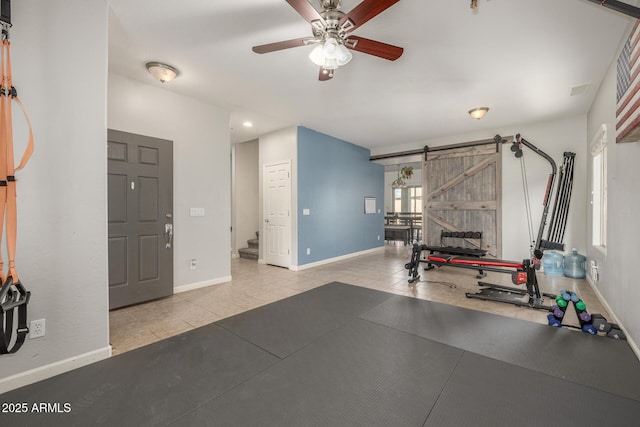 exercise area with ceiling fan, a barn door, and light tile patterned floors