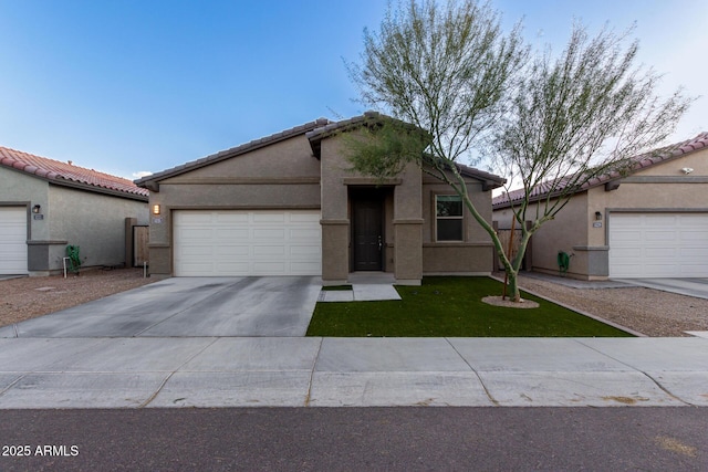 view of front of property with a garage, a tile roof, concrete driveway, stucco siding, and a front yard