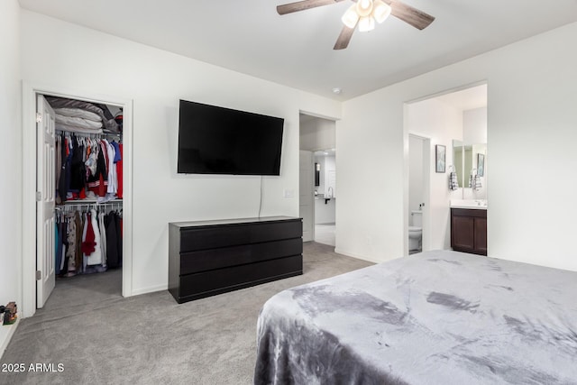 carpeted bedroom with a spacious closet, a ceiling fan, a closet, and ensuite bathroom