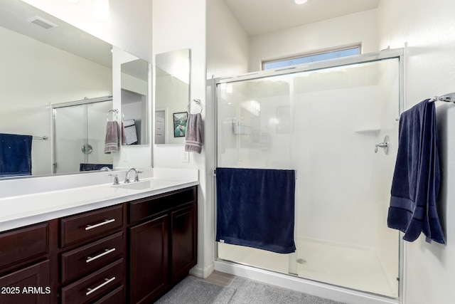 full bath with a stall shower, vanity, and visible vents