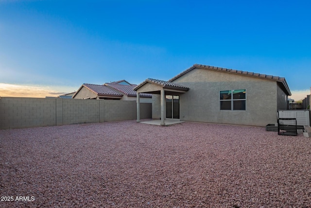 rear view of property featuring a fenced backyard, a tiled roof, a patio, and stucco siding