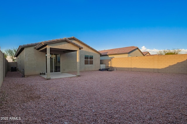 rear view of property featuring a patio area, a fenced backyard, a tiled roof, and stucco siding