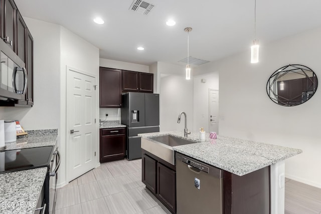 kitchen with visible vents, appliances with stainless steel finishes, a kitchen island with sink, a sink, and dark brown cabinetry