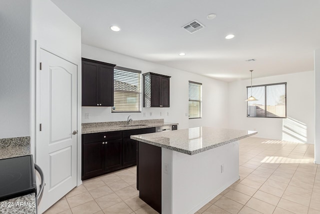 kitchen with pendant lighting, a kitchen island, a healthy amount of sunlight, and sink