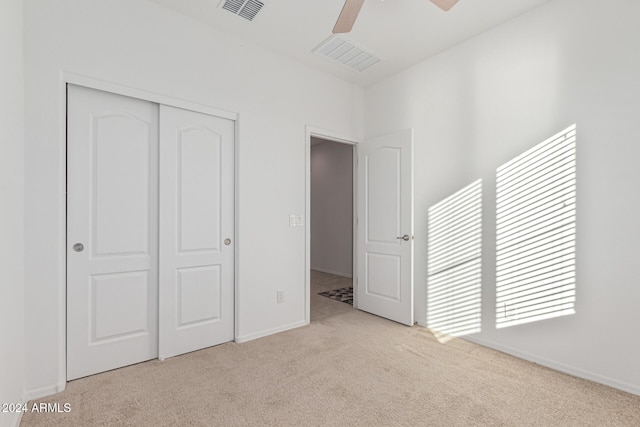 unfurnished bedroom featuring light colored carpet, a closet, and ceiling fan