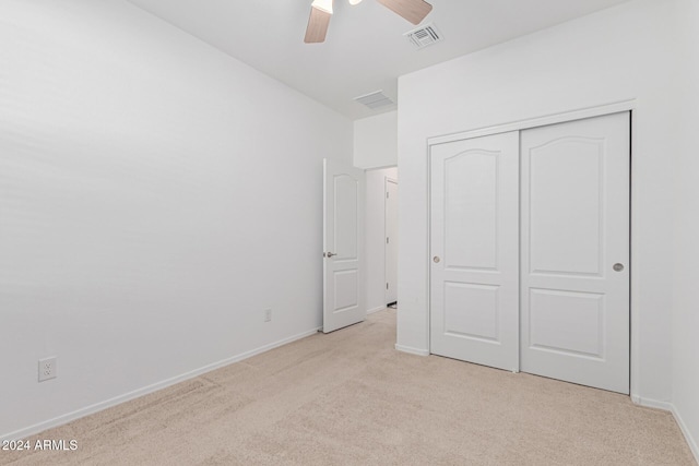 unfurnished bedroom featuring light carpet, a closet, and ceiling fan