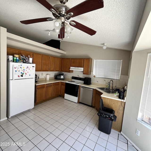 kitchen with freestanding refrigerator, electric range, stainless steel dishwasher, a sink, and under cabinet range hood