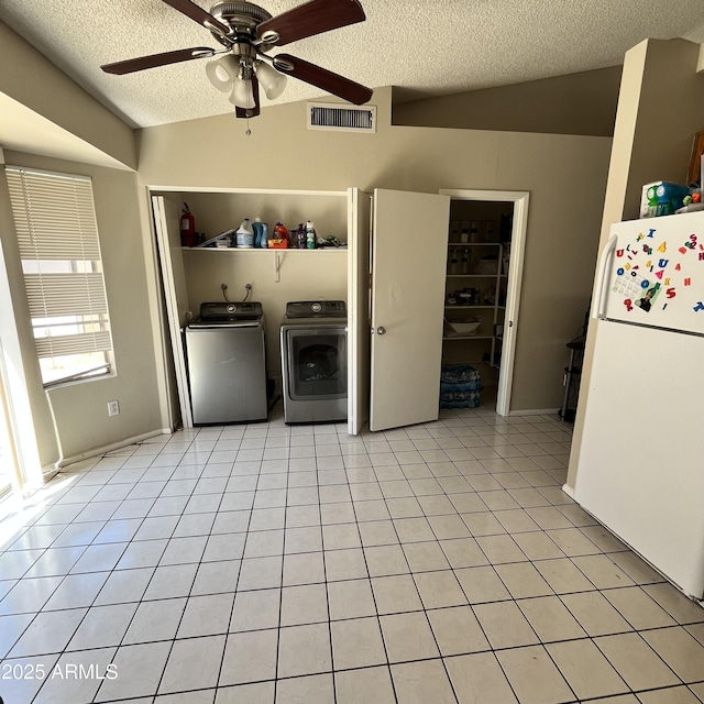 washroom featuring a textured ceiling, a ceiling fan, washer and clothes dryer, and light tile patterned flooring