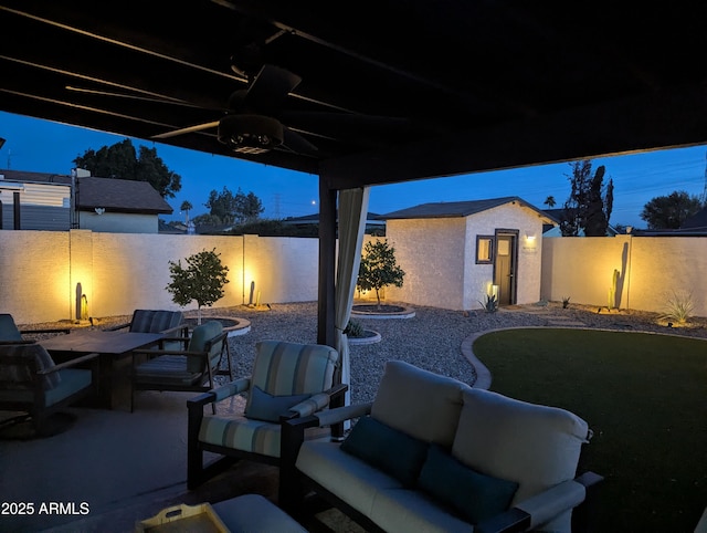 patio terrace at dusk with ceiling fan, a storage unit, and outdoor lounge area