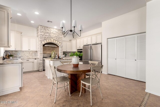 kitchen featuring visible vents, a sink, stainless steel appliances, decorative backsplash, and light tile patterned flooring