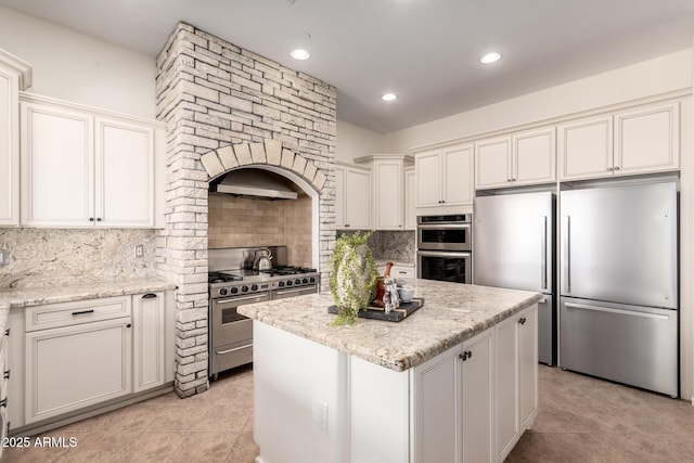 kitchen with backsplash, high end appliances, a kitchen island, and light stone counters