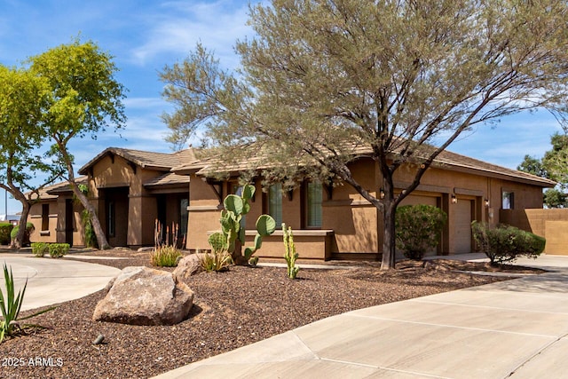 view of front facade featuring an attached garage, driveway, and stucco siding