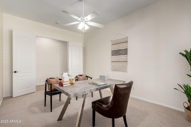dining area with ceiling fan, light colored carpet, and baseboards