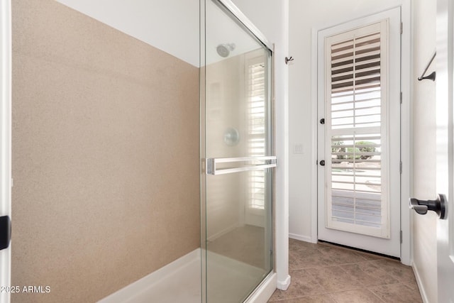 full bath featuring tile patterned flooring, baseboards, and a stall shower