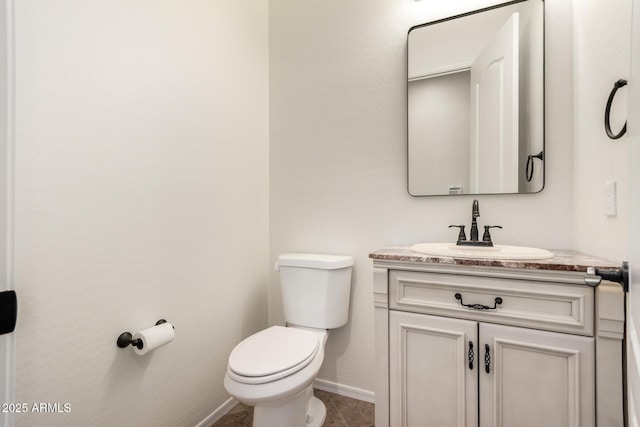 half bathroom with toilet, vanity, and baseboards