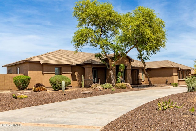 ranch-style house featuring concrete driveway, stucco siding, and a tile roof