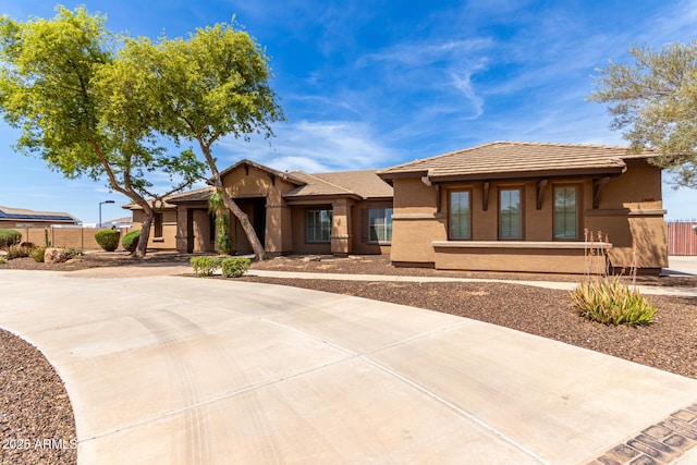 view of front facade featuring stucco siding, fence, and a tile roof