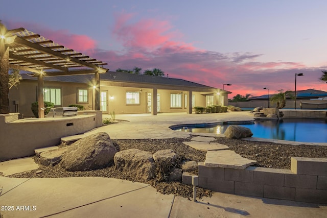 pool at dusk featuring a fenced in pool, a patio area, and an outdoor kitchen