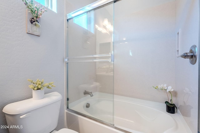 bathroom with toilet and combined bath / shower with glass door