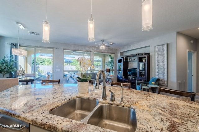 kitchen with pendant lighting, sink, light stone countertops, and ceiling fan