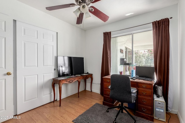home office with baseboards, ceiling fan, and light wood-style floors