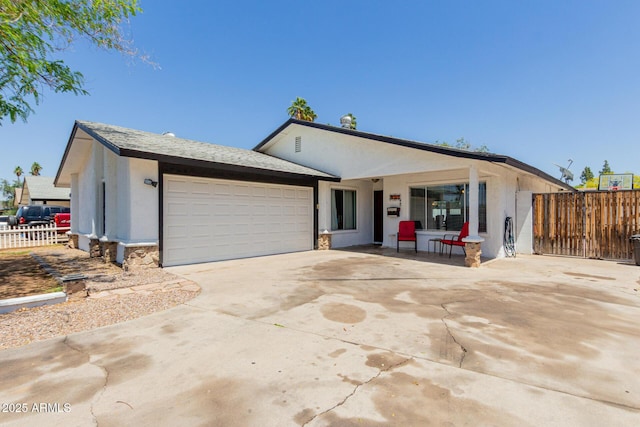 ranch-style house featuring an attached garage, fence, driveway, and stucco siding