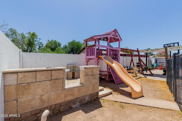 view of jungle gym featuring a fenced backyard, an outdoor structure, and a shed