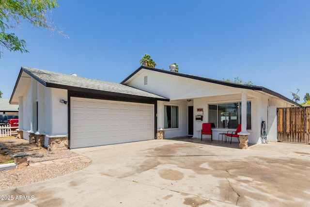 ranch-style home with a garage, fence, concrete driveway, stone siding, and stucco siding