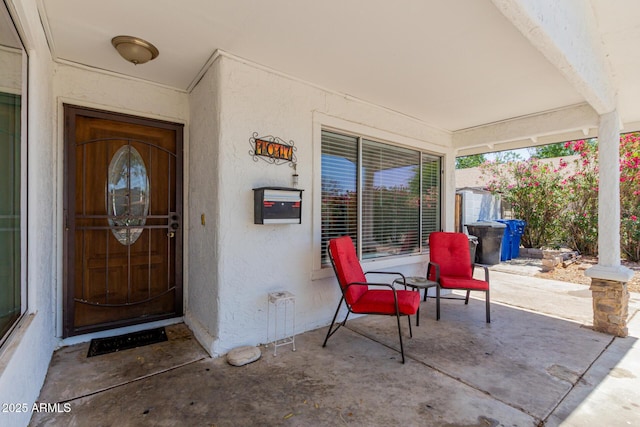 view of exterior entry with a porch and stucco siding