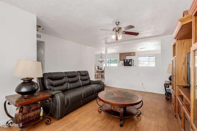 living room with ceiling fan with notable chandelier, wood finished floors, and visible vents