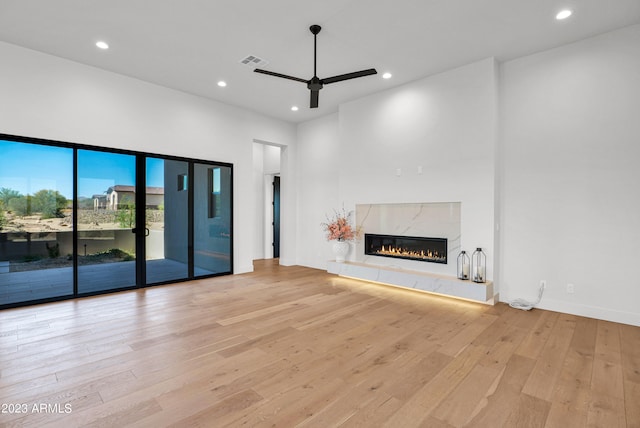 unfurnished living room featuring a fireplace, light wood-type flooring, and ceiling fan