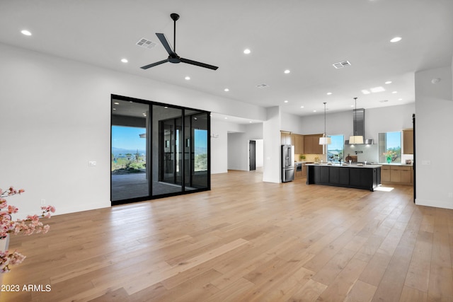 unfurnished living room featuring ceiling fan and light wood-type flooring