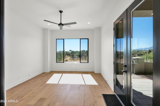 empty room with ceiling fan, light wood-type flooring, and french doors