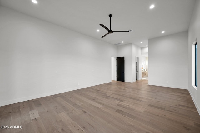 unfurnished room featuring wood-type flooring, ceiling fan, and a high ceiling