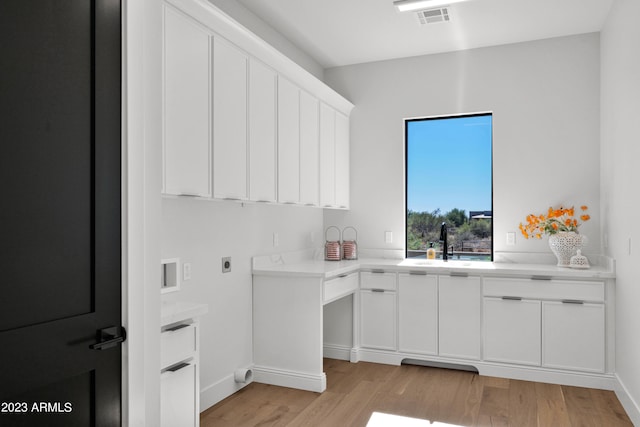 laundry area with hookup for an electric dryer, cabinets, light hardwood / wood-style flooring, and sink