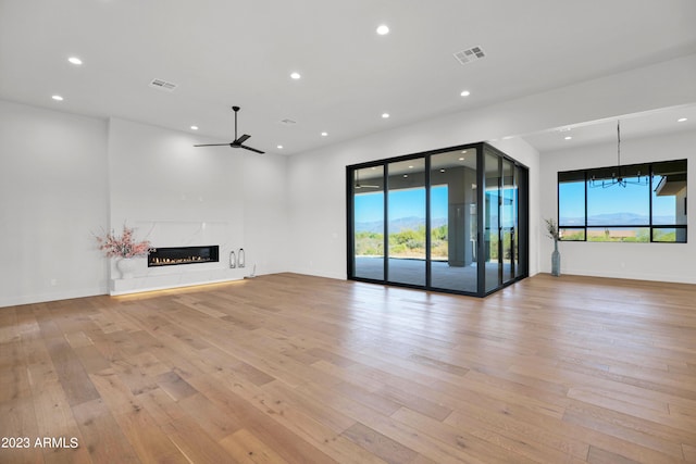 unfurnished living room with a wealth of natural light, a high end fireplace, and light hardwood / wood-style floors