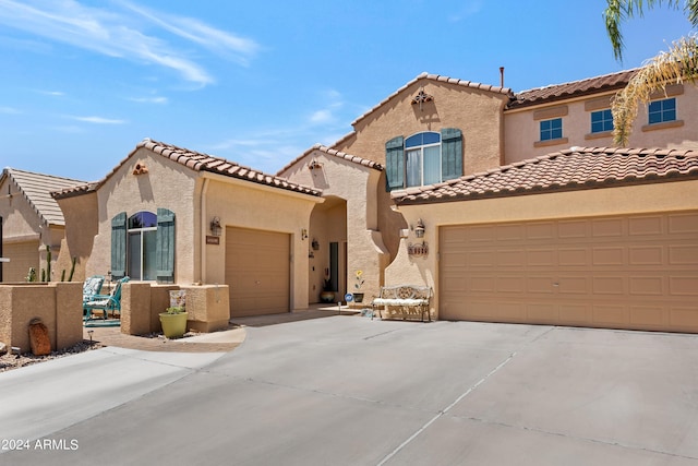 mediterranean / spanish-style home with a garage, driveway, a tile roof, and stucco siding