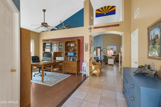 home office with arched walkways, light tile patterned floors, visible vents, a healthy amount of sunlight, and ceiling fan