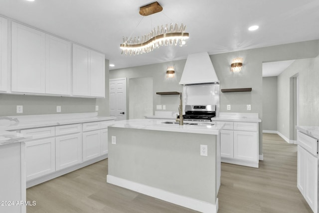 kitchen featuring a center island with sink, white cabinets, custom range hood, and light wood-type flooring