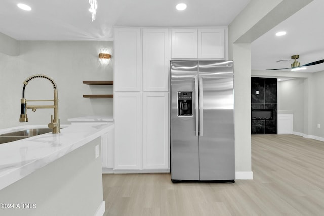 kitchen featuring stainless steel refrigerator with ice dispenser, white cabinetry, and sink