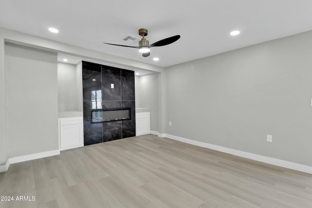 unfurnished room featuring ceiling fan, a fireplace, and light wood-type flooring