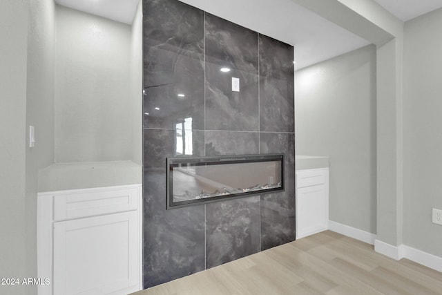 miscellaneous room featuring a tiled fireplace and light hardwood / wood-style flooring